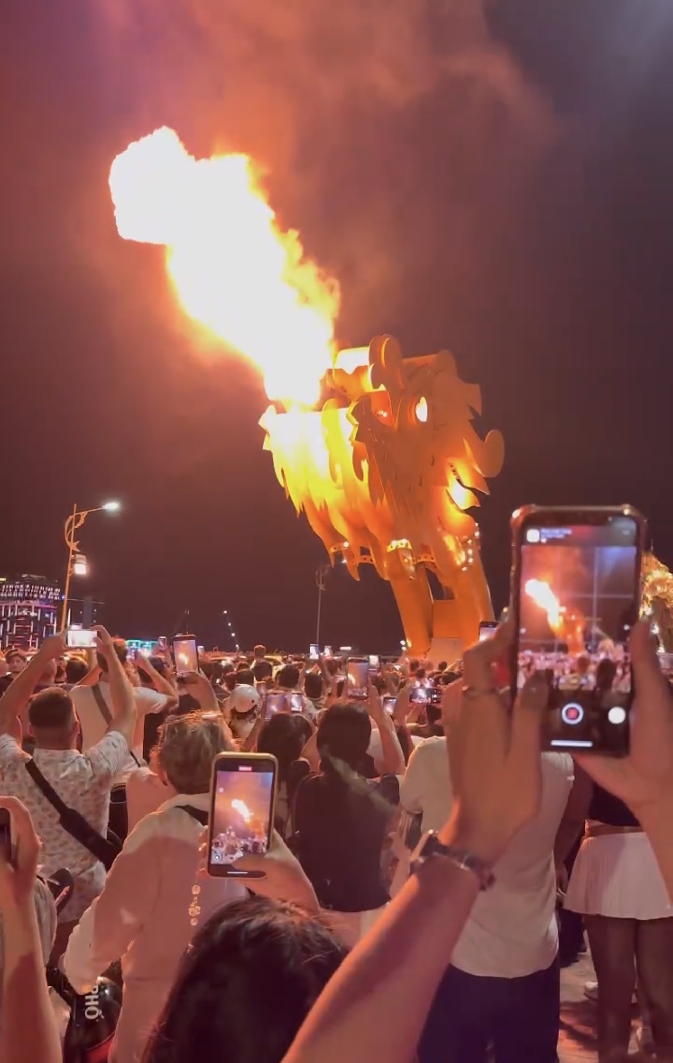 Dragon Bridge Da Nang breathing fire during the weekend show, with crowds watching from the riverbank