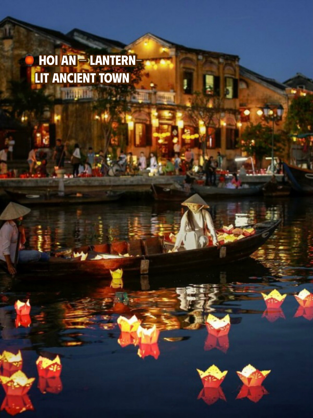 Floating flower lanterns on the Thu Bon River in front of the lantern-lit Hoi An Ancient Town at night