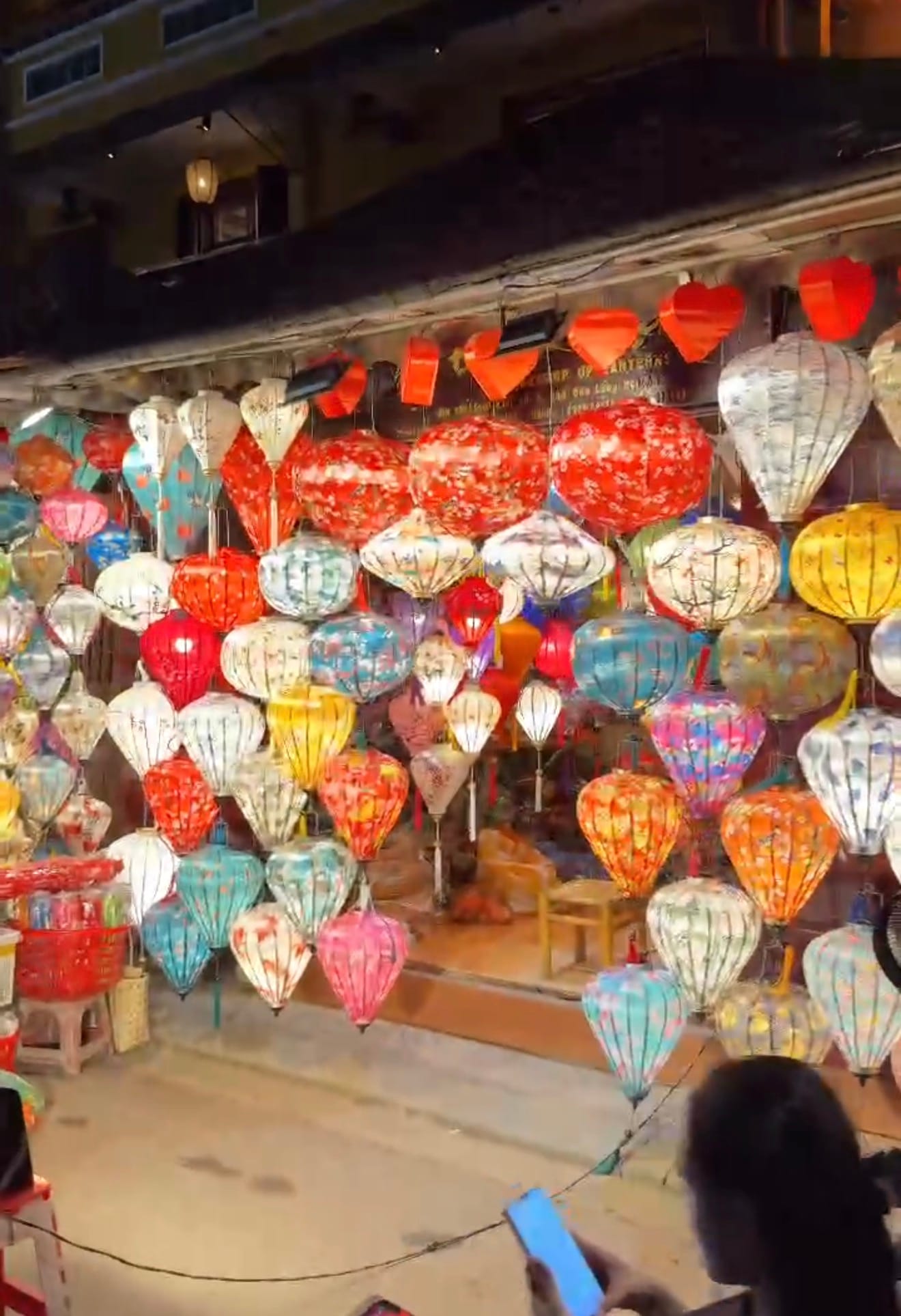 Hundreds of colourful handmade silk lanterns glowing at a lantern shop in Hoi An at night