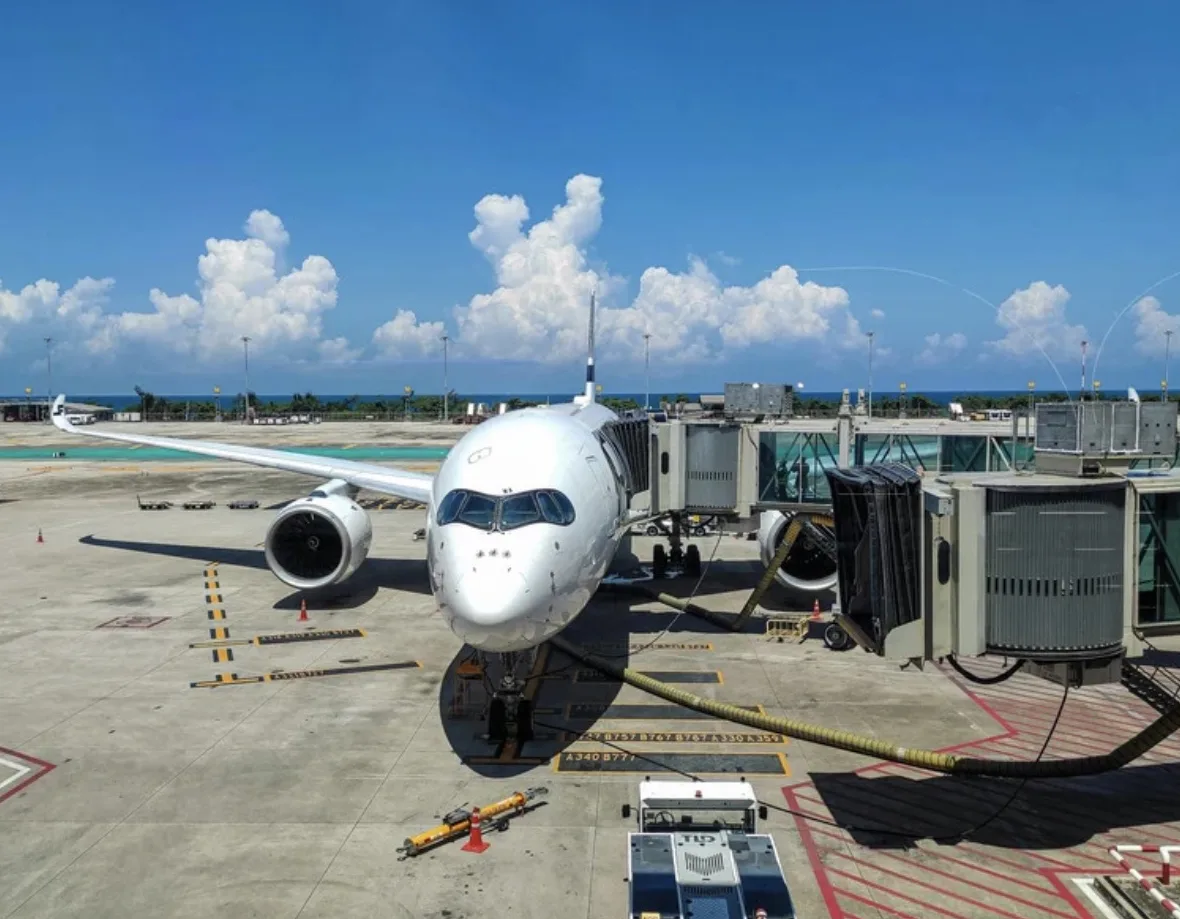 Airbus A350 at an airport gate on a sunny day, ready to board