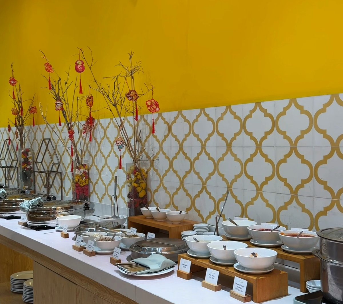 The breakfast buffet counter at An Bistro, with rows of dishes in front of a bright yellow wall and patterned tiles