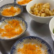Tray of bánh bèo bọt biển topped with orange cá chấy, with bowls of tóp mỡ and chili fish sauce, at Thanh Hải in Da Nang