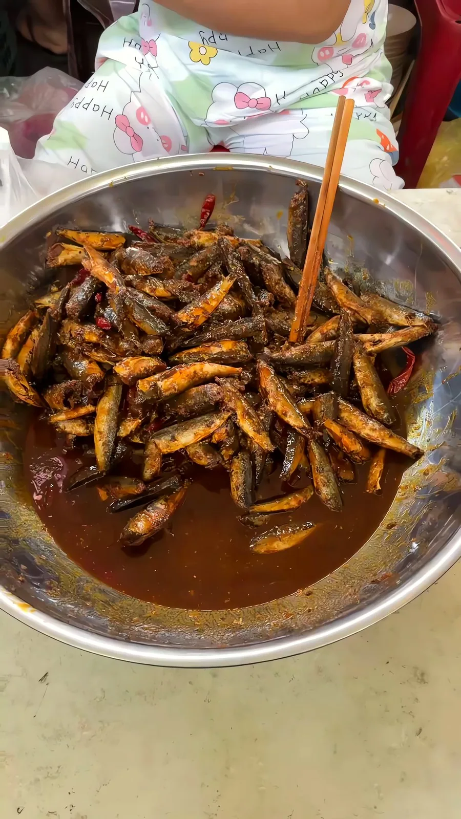 A big pot of cá nục (scad) braised in a dark, rich sauce at a cháo cá nục stall in Con Market