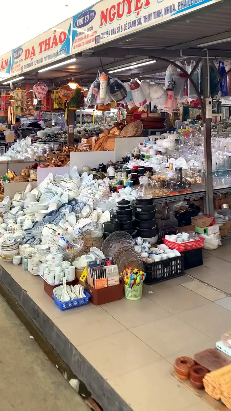 Rows of blue-and-white ceramic bowls, plates and kitchen tools at a homeware stall in Con Market, Da Nang