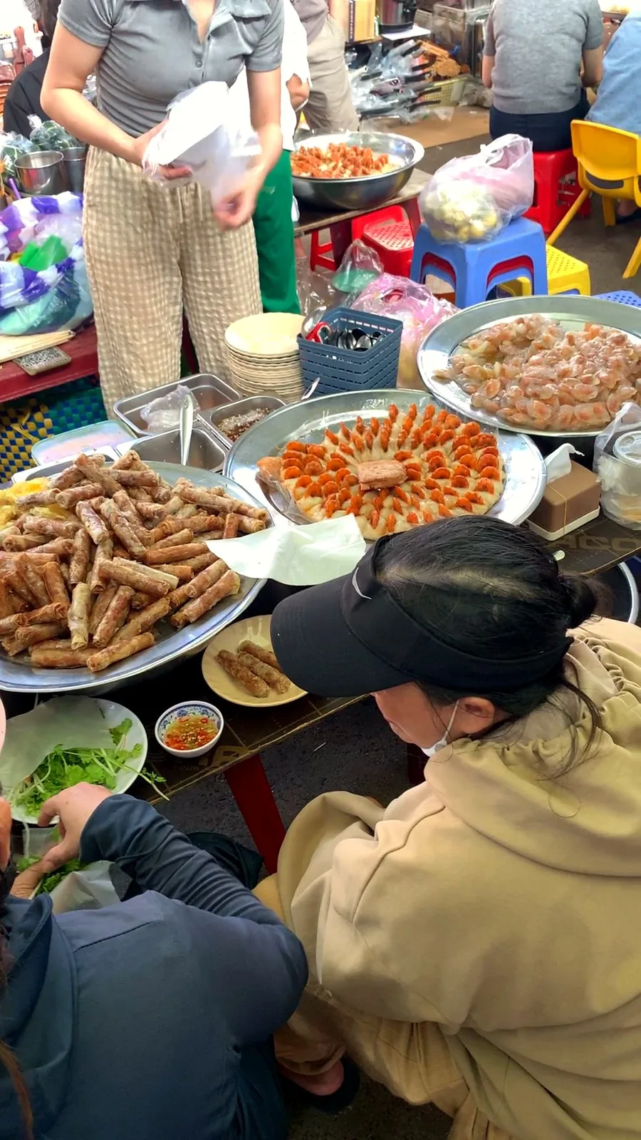 Trays of fried rolls and clear shrimp dumplings on a snack table at Con Market, seen from above