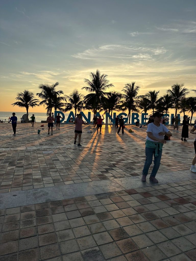 Locals exercising at sunrise by the Da Nang Beach sign on My Khe Beach