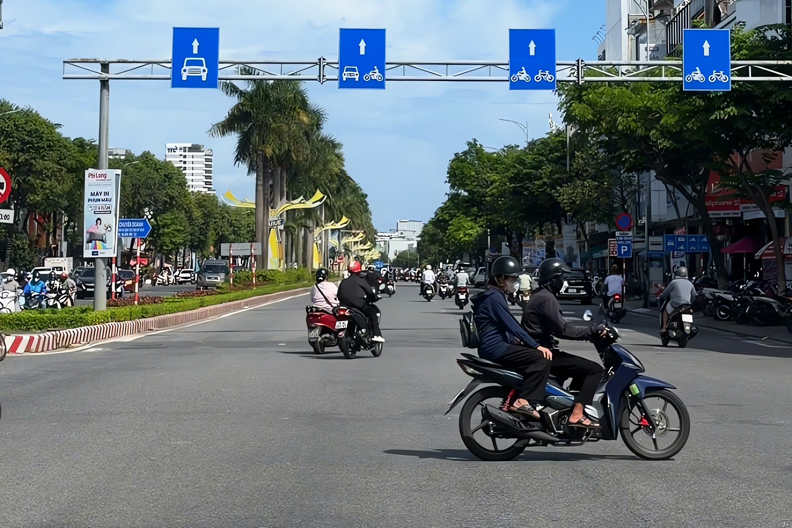 Motorbikes and cars on a wide street in Da Nang on a sunny day