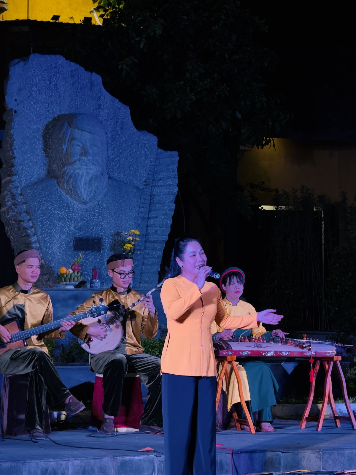 Folk singer in an orange ao dai with a traditional Vietnamese band at Kazik Park, Hoi An
