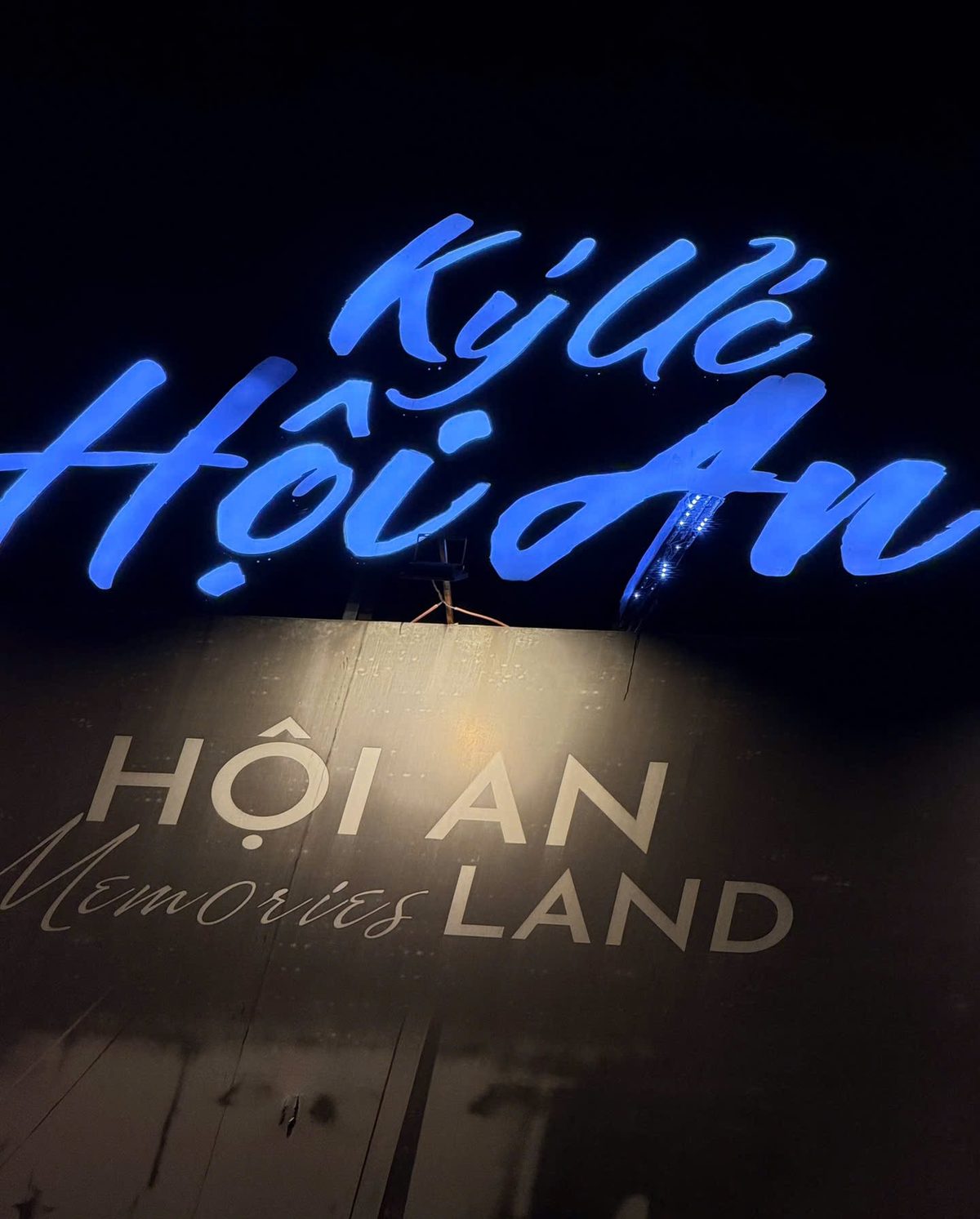 The glowing blue Ký Ức Hội An sign above the Hoi An Memories Land lettering at the entrance of the show park