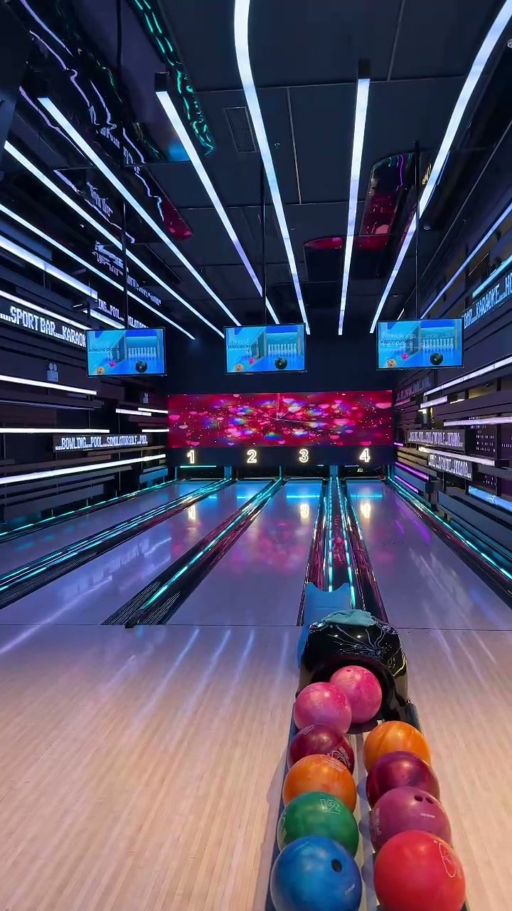 Neon-lit bowling lanes with a rack of colourful bowling balls at Hoiana Resort & Golf
