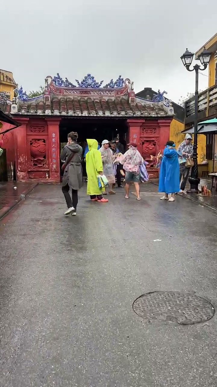 Visitors in rain ponchos at the Japanese Covered Bridge (Chùa Cầu) in Hoi An Old Town on a rainy day