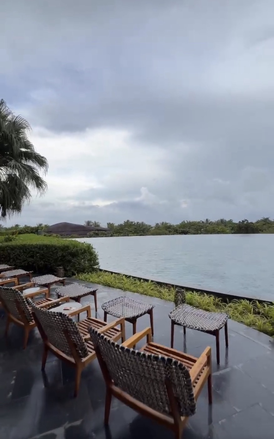 Empty wet loungers by the infinity pool under dark rain clouds at Hoiana Resort & Golf