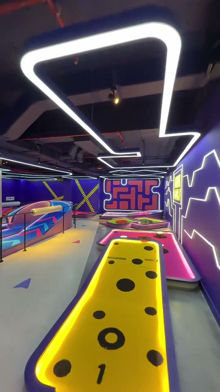 Glow-in-the-dark mini golf course with neon lights and a bright yellow hole at Hoiana Resort & Golf