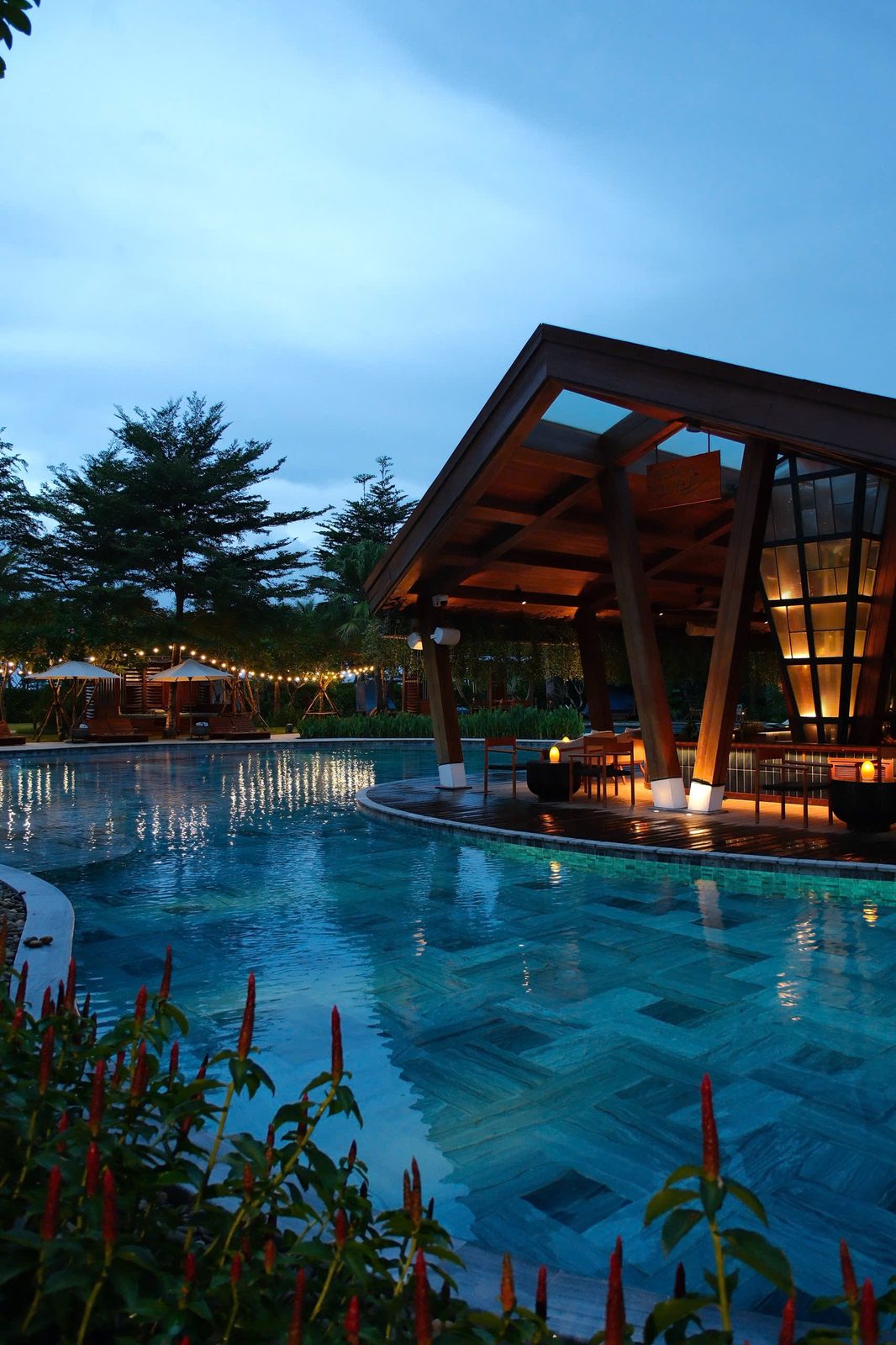 NOX Beach Club pool at blue hour with a lit pavilion and palm trees at Hoiana Resort & Golf, near Hoi An