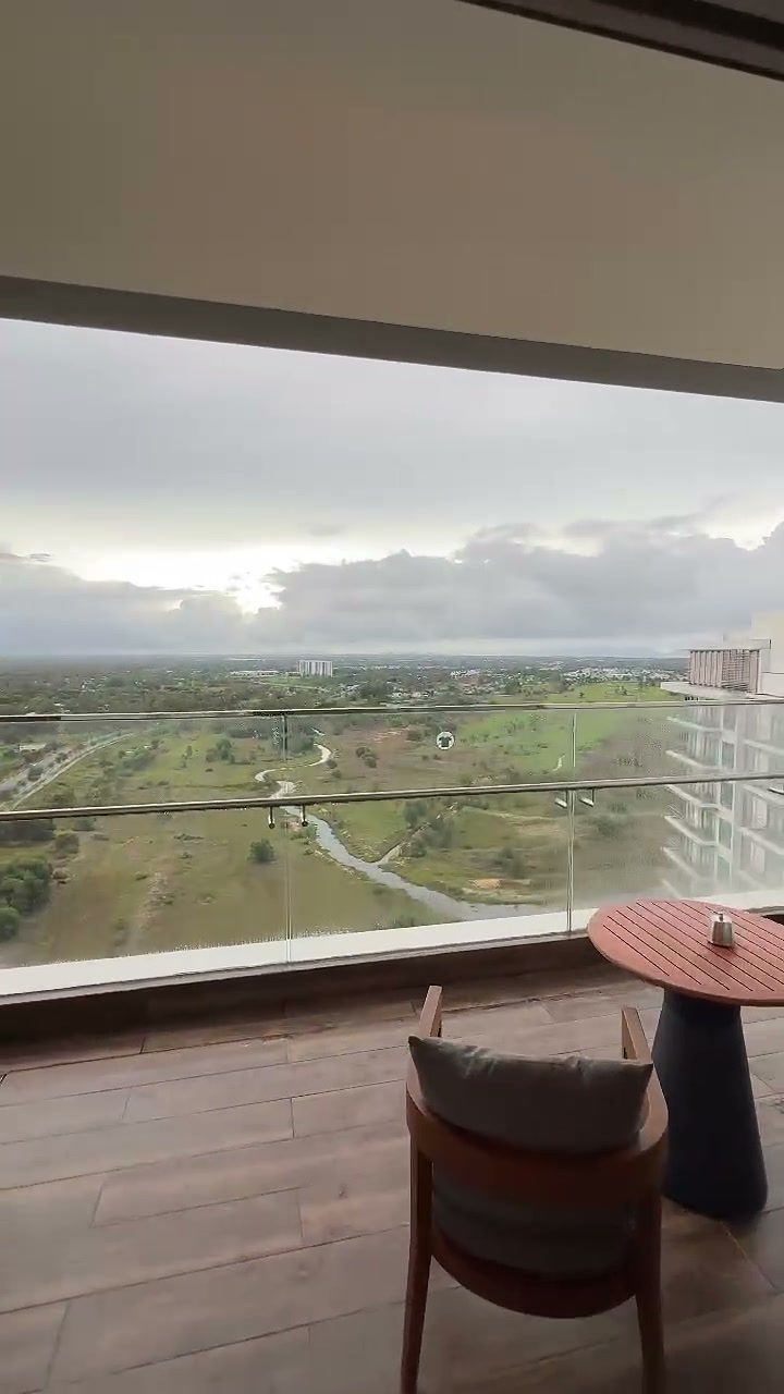 Balcony with a small table and chair looking over the golf course to the sea, New World Hoiana Hotel room