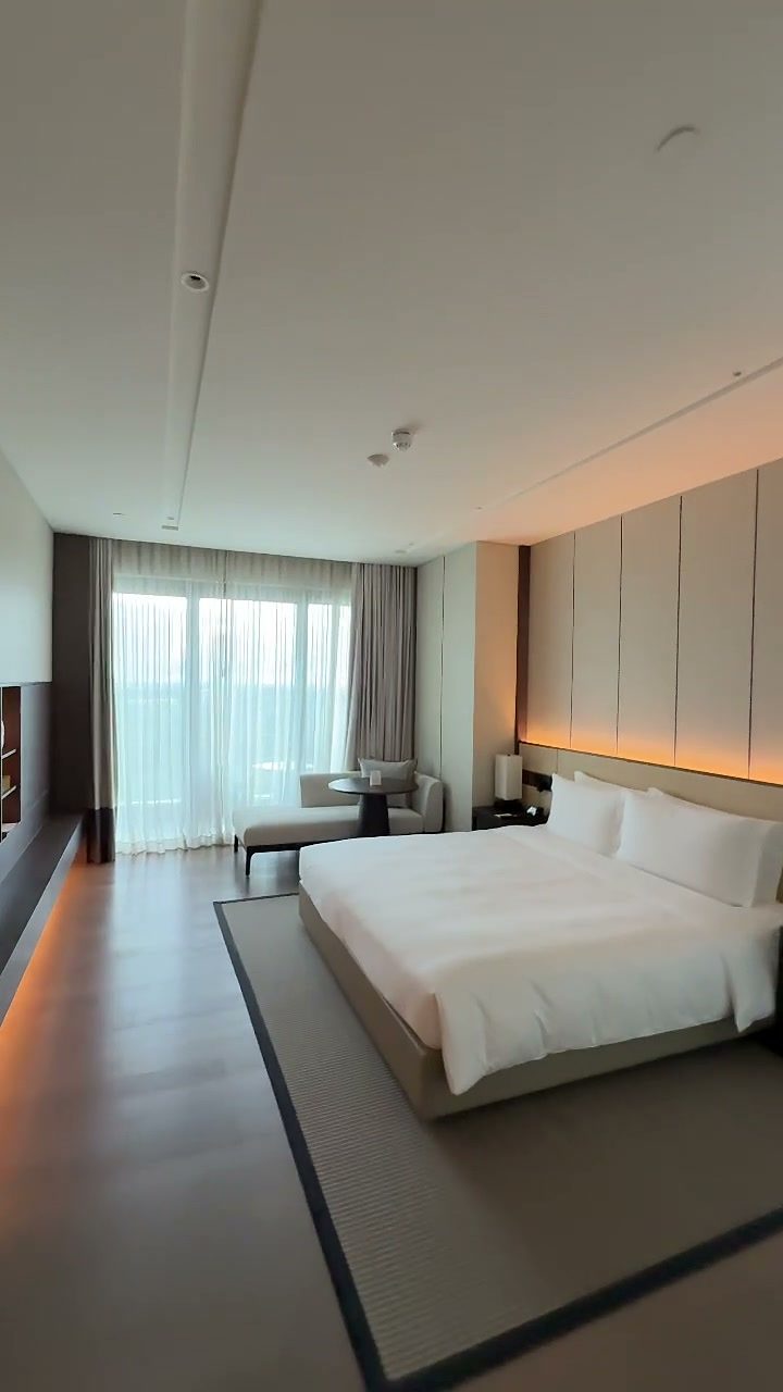 Calm hotel bedroom with a king bed, neutral tones and sheer curtains at New World Hoiana Hotel