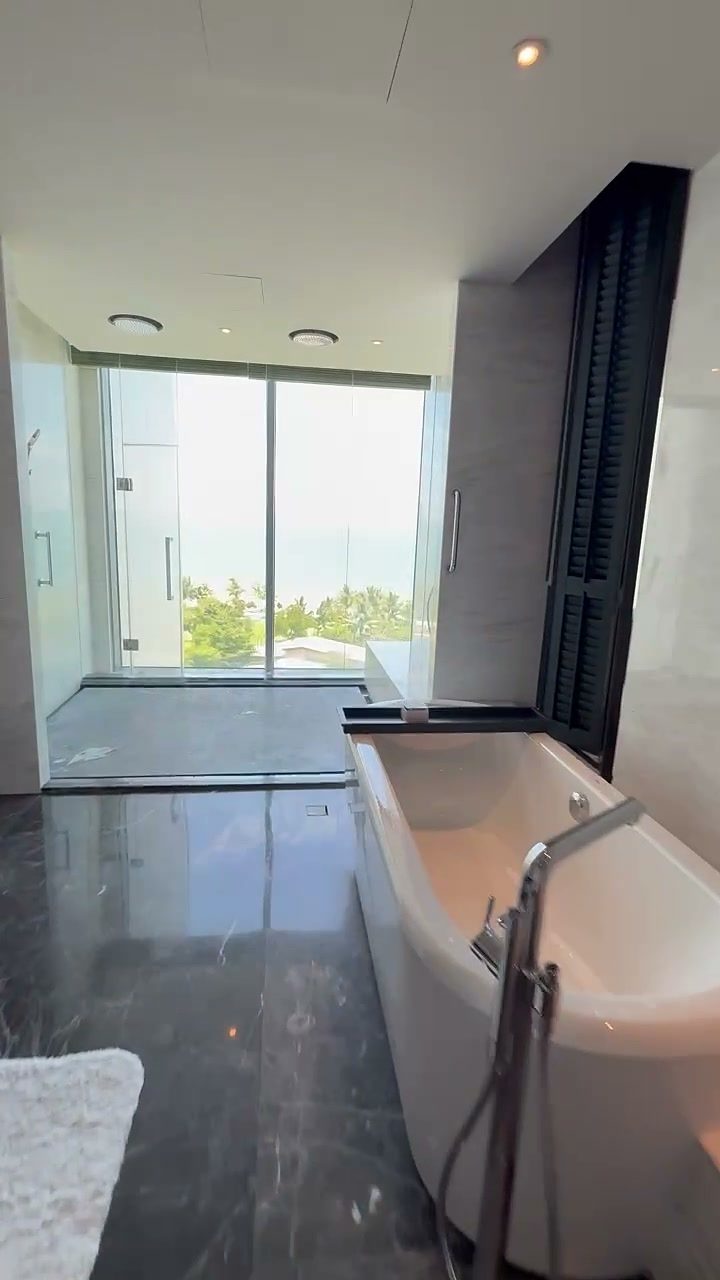 Freestanding bathtub beside a floor-to-ceiling window with a sea view in a suite at Hoiana Resort & Golf