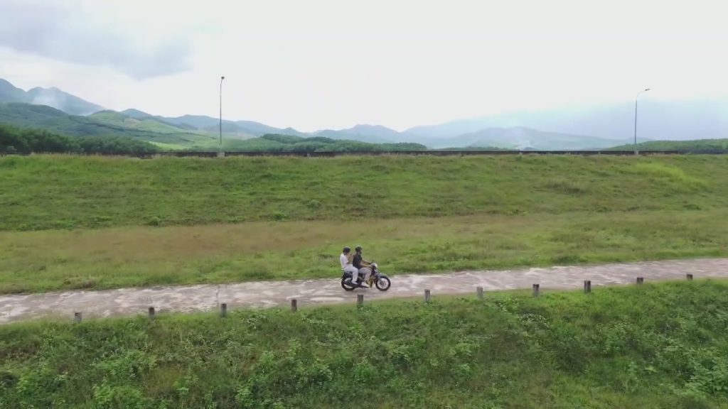 Motorbike riding along a dam road at Khe Tân Lake