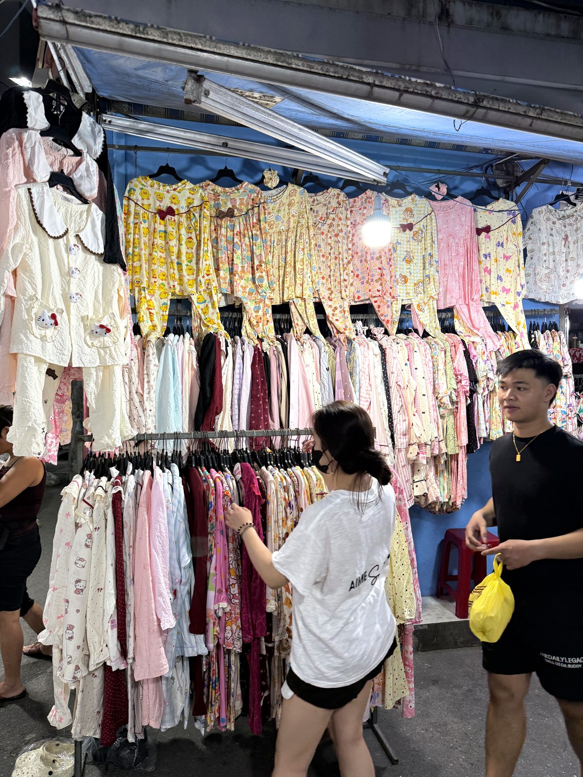 Racks of cheap T-shirts, dresses and casual clothes hanging at a stall in Le Duan Night Market, Da Nang