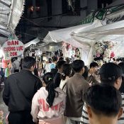A packed aisle of shoppers passing phone-accessory and hair-clip stalls at Le Duan Night Market, Da Nang