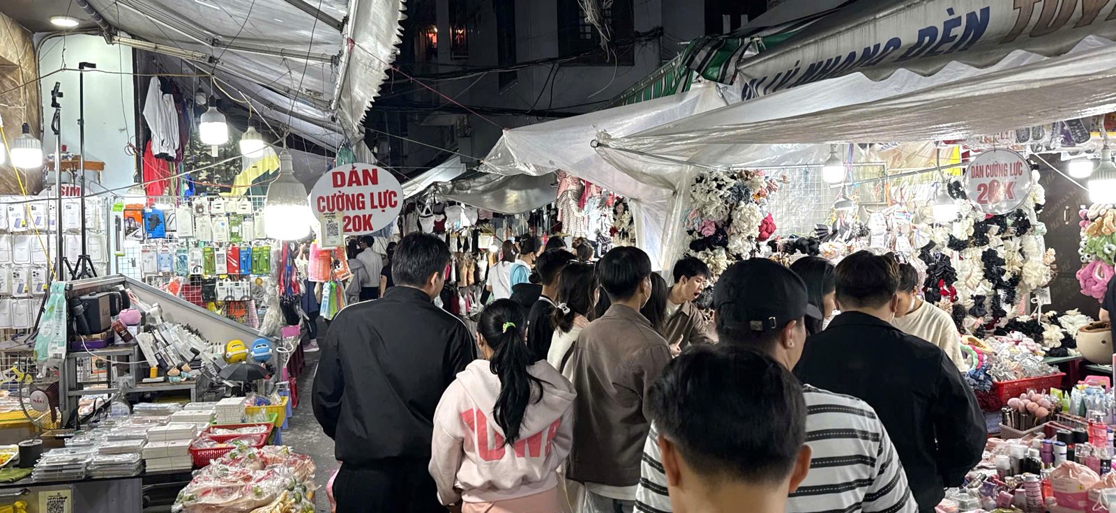 A packed aisle of shoppers passing phone-accessory and hair-clip stalls at Le Duan Night Market, Da Nang