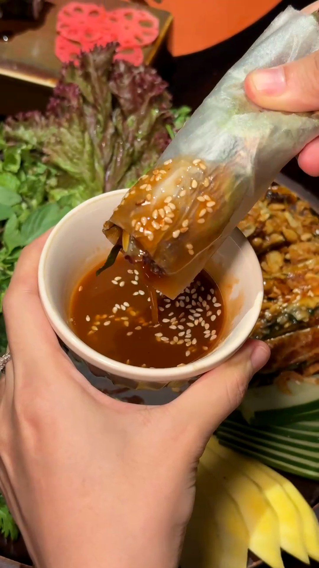 Dipping a hand-rolled mẹt cuốn into sesame sauce at Maha Vegetariano Da Nang