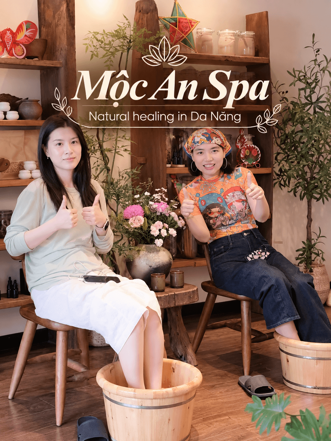 Two friends enjoying a herbal foot soak in wooden tubs at Mộc An Spa in Da Nang