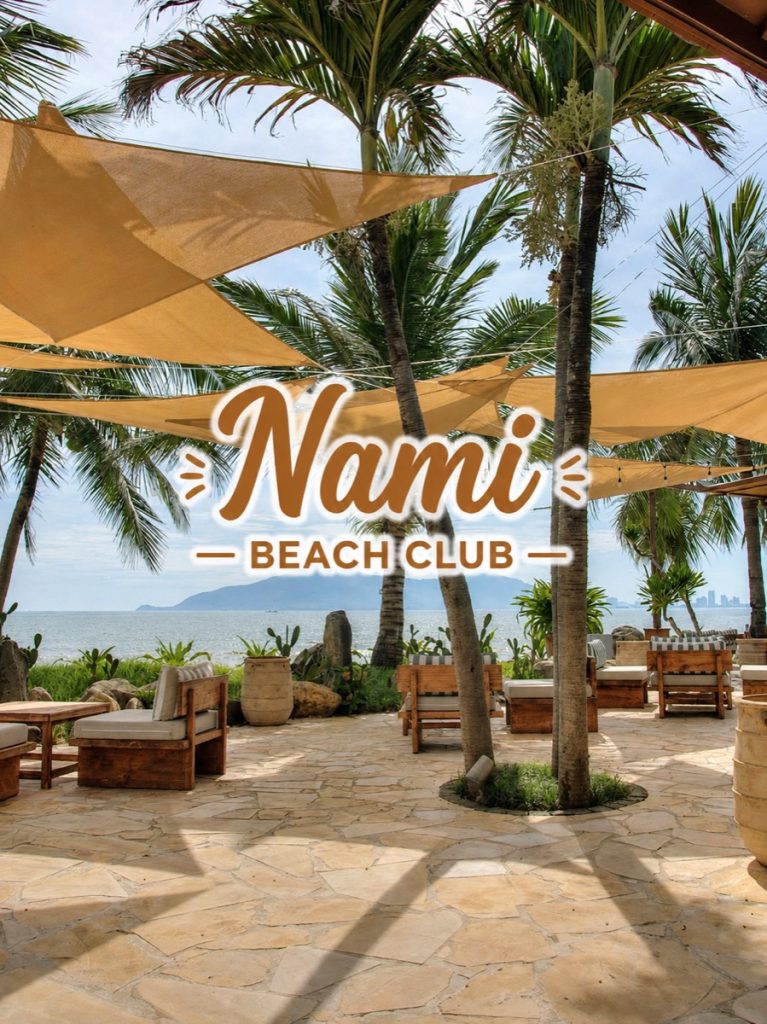 Shaded lounge terrace under palm trees facing Da Nang Bay at Nami Beach Club, Mikazuki resort