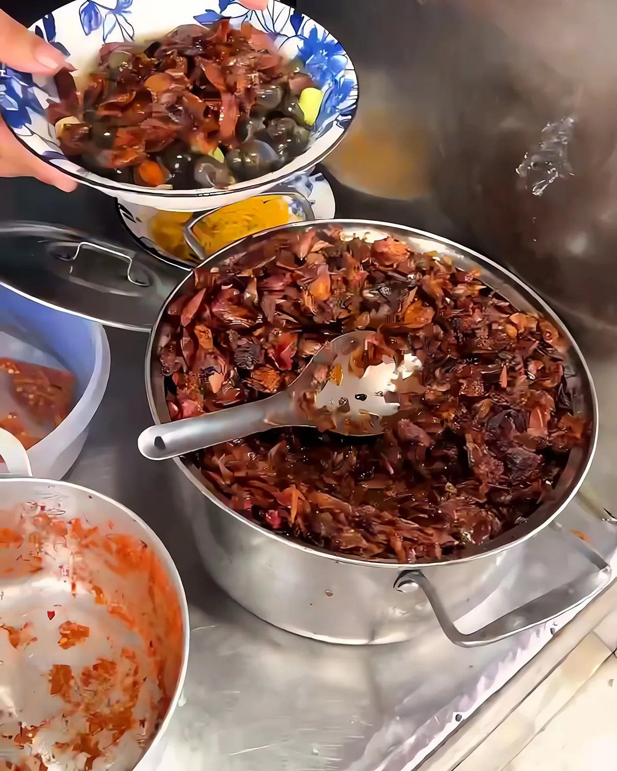 Pots of fried shallot and chili topping and red chili sauce on the counter of an ốc hút stall