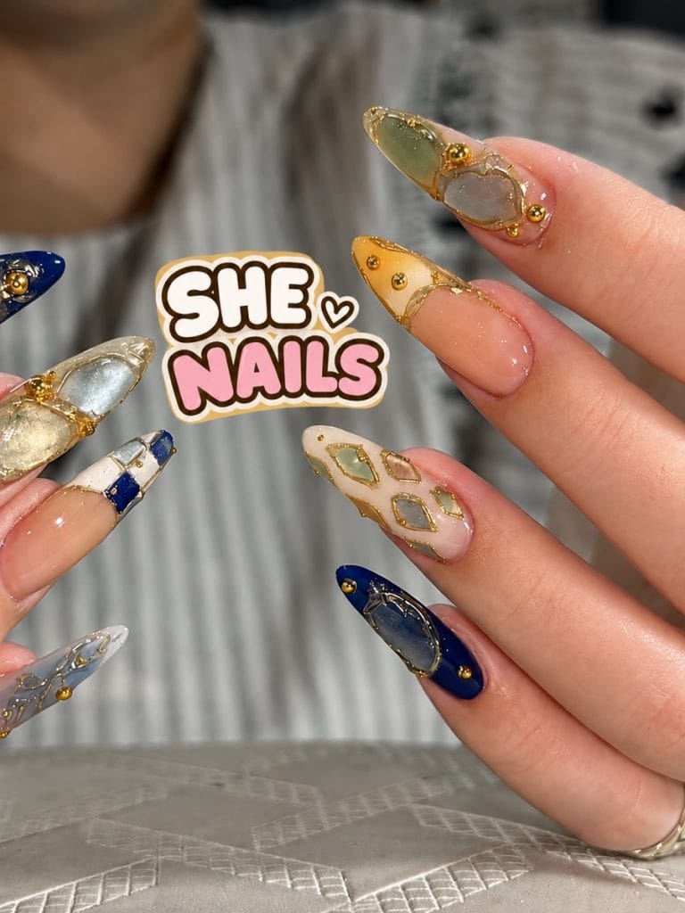 Long almond nails with gold-framed gem and stone designs from She Nails in Da Nang