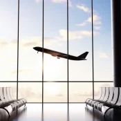 Plane taking off seen through the windows of an airport departure lounge
