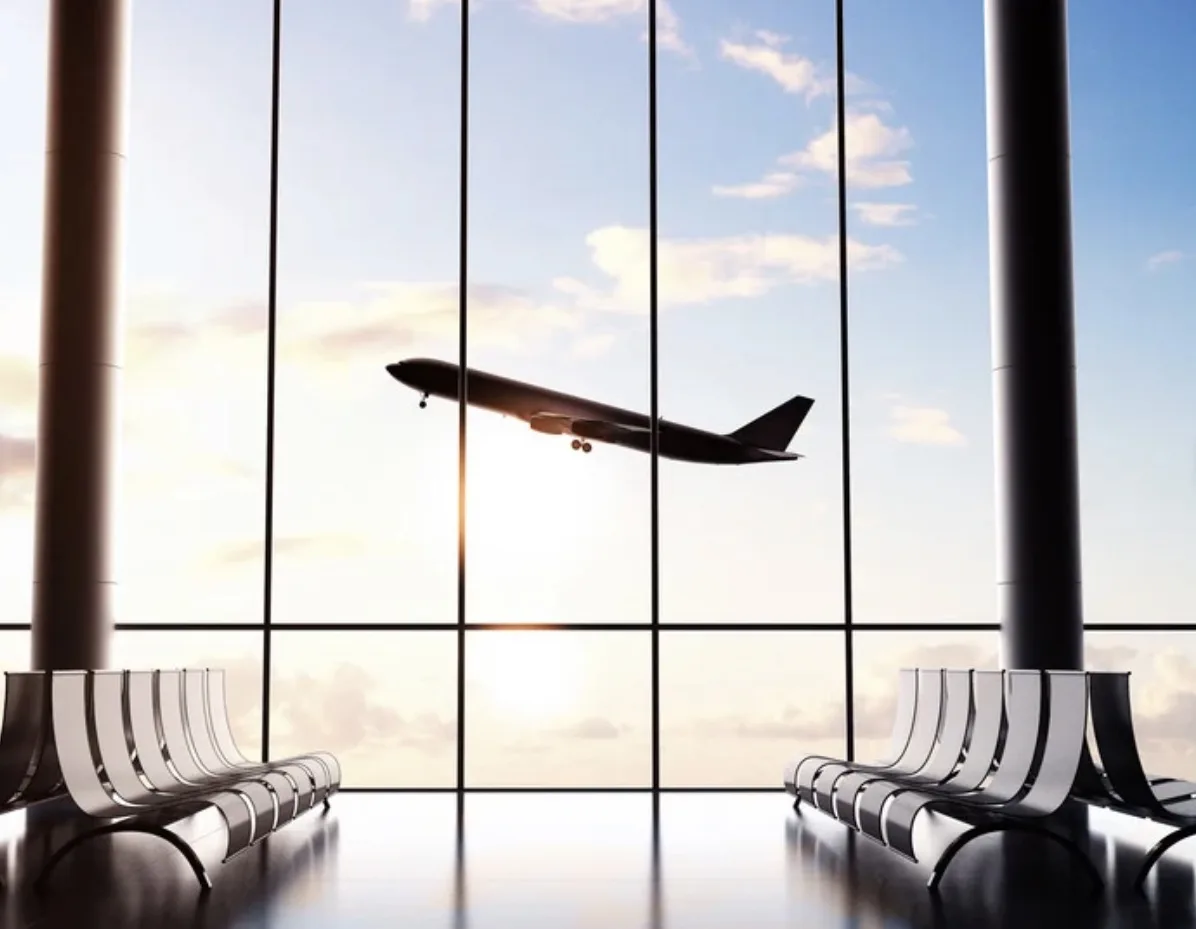 Plane taking off seen through the windows of an airport departure lounge