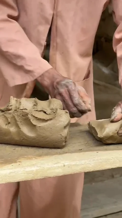 Artisan's hands kneading clay at a workbench in Thanh Ha Pottery Village, Hoi An
