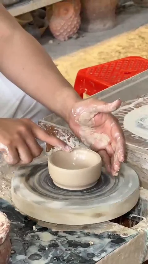 Hands shaping a small clay bowl on a pottery wheel during a hands-on try at Thanh Ha Pottery Village