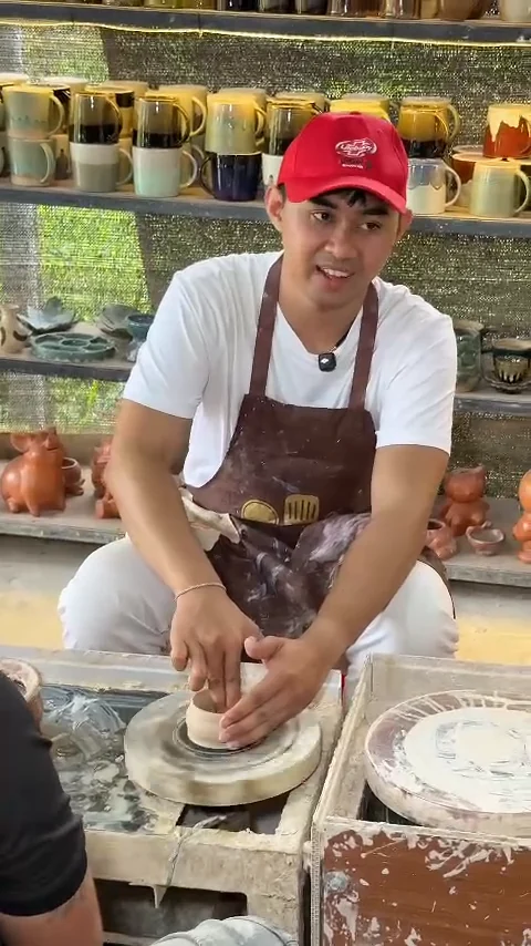 Visit Da Nang presenter in a red cap trying the pottery wheel at Thanh Ha Pottery Village, Hoi An