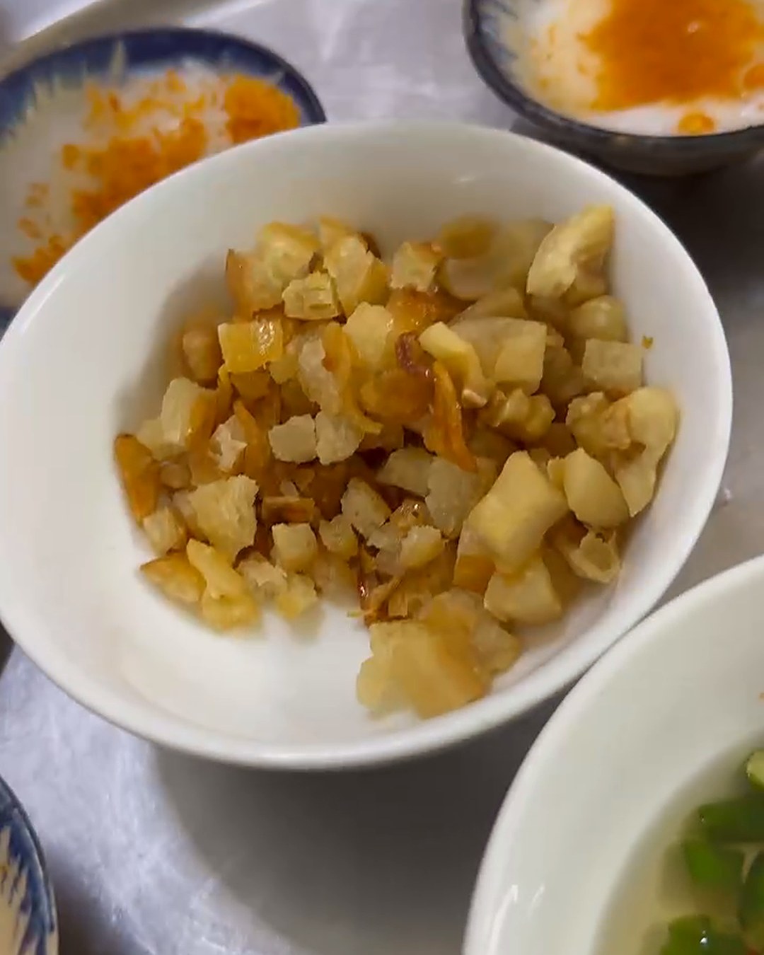 Bowl of crispy tóp mỡ pork crackling and fried bread with shallots for bánh bèo